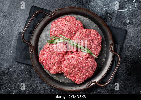 Ungekochte Frikadellen aus Hackfleisch, rohe Fleischschnitzel. Schwarzer Hintergrund. Draufsicht. Stockfoto