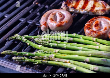 Schweinefleisch, Huhn und grüner Spargel auf einem Grill werden gegrillt. Hochwertige Fotos Stockfoto