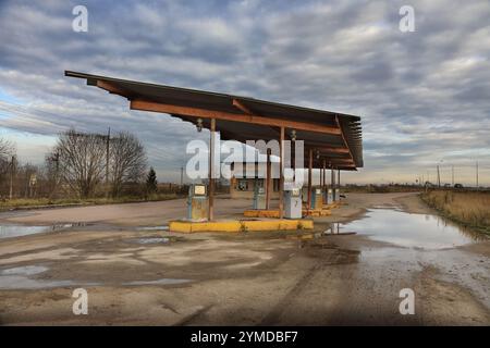 Die geisterhaften Überreste einer lange verlassenen Tankstelle vor Jahren vor dramatischem Himmel auf dem Land Stockfoto