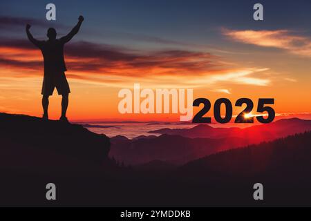 Mann auf dem Gipfel des Berges begrüßt den Sonnenaufgang des neuen Jahres 2025, wunderschöne Naturlandschaft Stockfoto