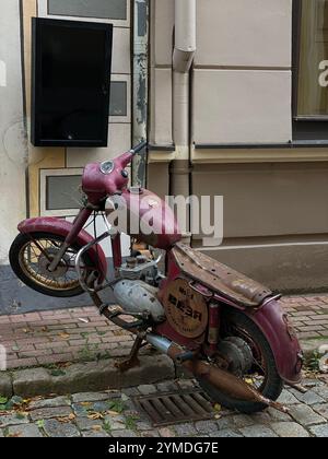 Ein rotes Motorrad mit den Buchstaben BHS auf dem Sitz. Er lehnt sich an eine Ziegelmauer. Lettland, Riga 08.10.2023 Stockfoto