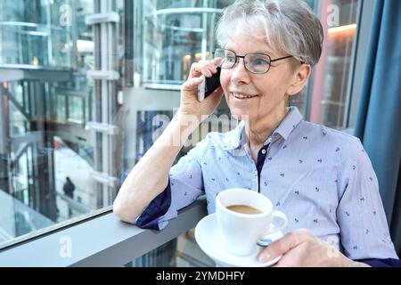 17. November 2024: Eine erfahrene Seniorin verbindet Tradition und Moderne. Sie ist mit Smartphone und Kaffee in der Hand am Telefon und symbolisiert Senioren im digitalen Zeitalter *** eine erfahrene Seniorin verbindet Tradition und Moderne. Sie telefoniert mit dem Smartphone und Kaffee in der Hand, symbolisch für Senioren im digitalen Zeitalter Stockfoto