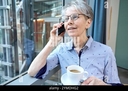 17. November 2024: Eine erfahrene Seniorin verbindet Tradition und Moderne. Sie ist mit Smartphone und Kaffee in der Hand am Telefon und symbolisiert Senioren im digitalen Zeitalter *** eine erfahrene Seniorin verbindet Tradition und Moderne. Sie telefoniert mit dem Smartphone und Kaffee in der Hand, symbolisch für Senioren im digitalen Zeitalter Stockfoto