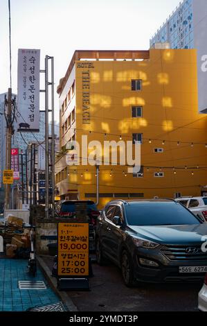 Urbane Straßenszene mit gelber Hotelfassade, Autos und Beschilderung in Busan, Südkorea. Stockfoto