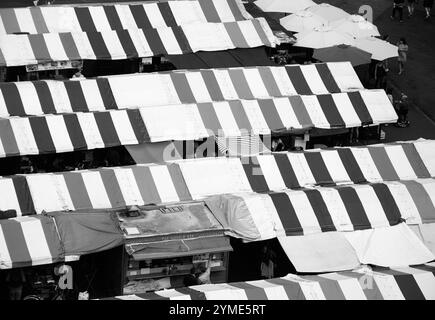 CAMBRIDGE, Großbritannien - 16. AUGUST 2017: Blick auf farbenfrohe Marktstände am historischen Marktplatz von Cambridge. Junge Männer kaufen Nudeln. Schwarzweißfoto Stockfoto