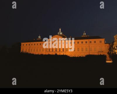 Ein großes Gebäude mit einem hohen Turm und einer Uhr auf dem Turm. Das Gebäude ist nachts beleuchtet Stockfoto