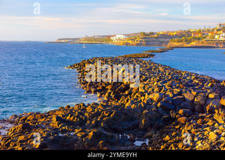 Las Americas an der Costa Adeje auf Teneriffa auf den Kanarischen Inseln. Ruhige Aussicht auf ein großes Gewässer umgeben von Felsen, mit einem kleinen Boot sanft flo Stockfoto