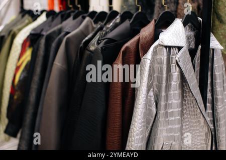 Verschiedene stilvolle Lederjacken hängen in einer Reihe an Kleiderbügeln in einer Mode-Luxusboutique, herbstlichen Stoffkollektion Stockfoto