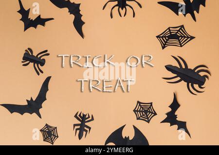 Trick or Treat ist in weißen Buchstaben auf einem Hintergrund aus schwarzen Fledermäusen und Spinnen geschrieben. Das Bild ist eine Collage von Halloween-Ausschnitten, einschließlich BA Stockfoto