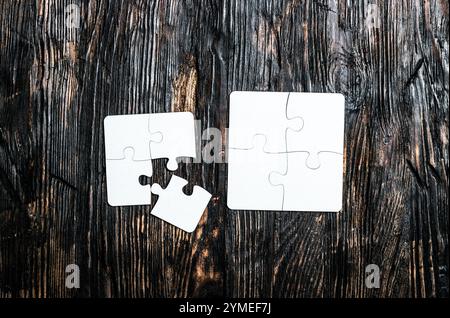 Zwei kleine weiße Puzzles auf dunklem Holztisch Stockfoto