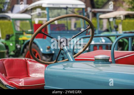 Detail eines Traktors mit rotem Sitz und Lenkrad im Vordergrund, Südlohn, münsterland, deutschland Stockfoto