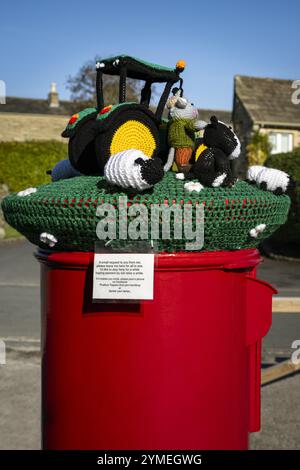 Nahaufnahme der Garn Bomb auf rotem Briefkasten (Farm-Szene, dekorative Garn-Bombing Street Art, Etikett) - Bolton Abbey Village, North Yorkshire, England, Großbritannien. Stockfoto