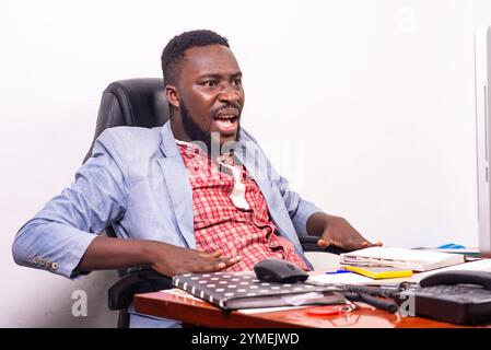 Der junge Geschäftsmann war erstaunt und überrascht, als er im Büro auf den Laptop-Bildschirm schaute. Stockfoto