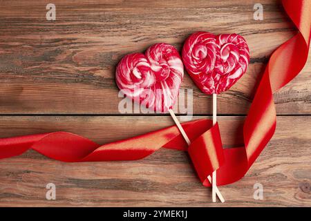 Rote Herzlutscher. Lockiges Band in der Nähe von Süßigkeiten. Nachtisch für zwei Personen Stockfoto