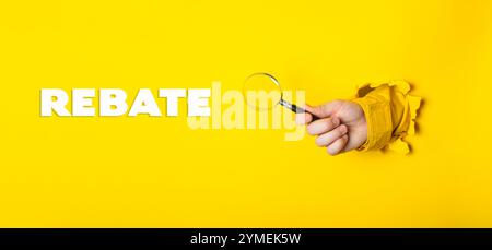 Hand mit einer Lupe auf gelbem Hintergrund, unten steht das Wort „RABATTE“ Stockfoto