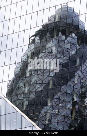 Wolkenkratzer mit reflektierenden Glaspaneelen, die verzerrte Reflexionen eines anderen Gebäudes zeigen, London, Großbritannien Stockfoto