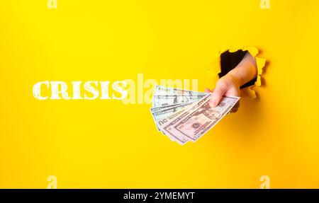 Hand hält einen Stapel Geld mit dem Wort Krise darunter. Konzept der Dringlichkeit und der finanziellen Instabilität Stockfoto