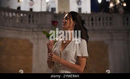 Romantische Pose. Frau mit Rose auf der historischen Treppe in Rom bei Nacht Stockfoto