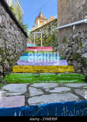 Das künstlerische und kulturelle Projekt Escalera de colores zeigt farbenfrohe Schritte mit bedeutungsvollen Phrasen in Ribadesella, Asturien, Spanien Stockfoto