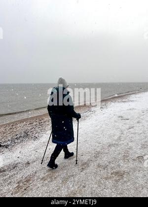 Einsame Seniorin, die an einem kalten Wintertag an der Ostseeküste in Danzig, Polen, Europa entlang des schneebedeckten Strandes von Danzig spaziert Stockfoto