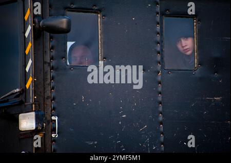 Zwei neugierige Amish-Kinder (ein Junge und ein Mädchen) schauen auf dem Weg zur Schule aus dem Fenster eines Pferdewagens. Stockfoto