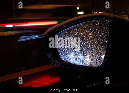 München, Deutschland. November 2024. Autos fahren im Schnee über die Landshuter Allee auf dem Mittleren Ring und spiegeln sich im Außenspiegel eines Autos. Der Deutsche Wetterdienst (DWD) hat eine Unwetterwarnung vor starkem Schneefall in Teilen Bayerns ausgegeben. Quelle: Sven Hoppe/dpa/Alamy Live News Stockfoto