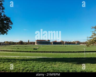 Ein großes Gebäude mit einem roten Dach befindet sich auf einem Feld. Der Himmel ist klar und blau. Das Gebäude ist von einem Zaun umgeben Stockfoto