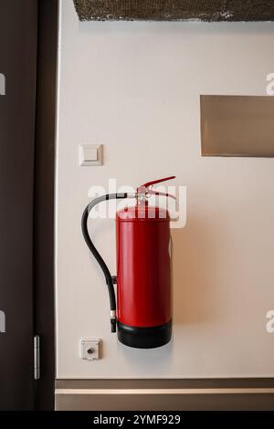 Feuerlöscher hängt an der Lichtwand im Gebäude Stockfoto
