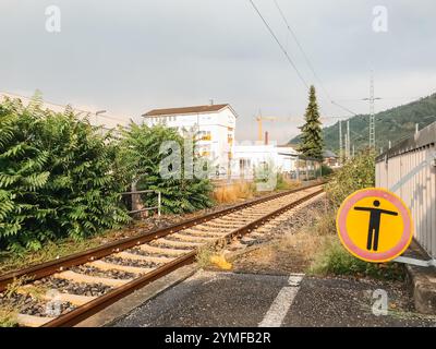 Ein Eisenbahngleis mit einem gelben Schild, das besagt, dass nicht betreten wird, und eine Person mit ausgestreckten Armen Stockfoto