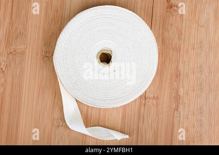 Eine Rolle Taftband aus dickem Baumwollgewebe auf einer Holzoberfläche. Kopierbereich. Stockfoto