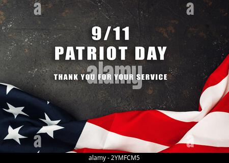 Patriotische Flagge mit den Worten 911 Patriot Day darunter. Die Flagge steht auf einem dunklen Hintergrund und die Wörter sind weiß geschrieben Stockfoto