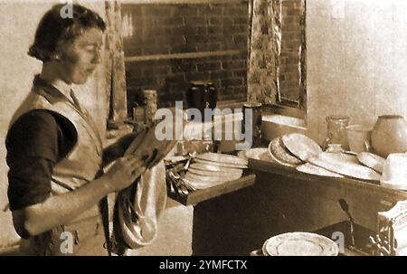 Das Heimleben in den 1940er Jahren in Großbritannien. Eine typische britische Hausfrau aus den 1940er Jahren, die sich in ihrer Küche abspülte Stockfoto