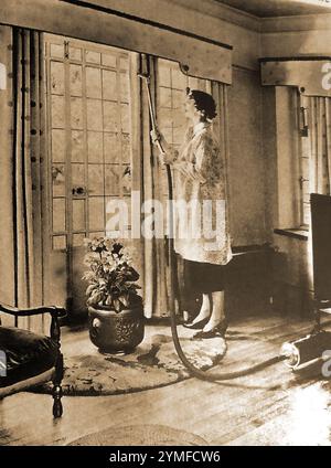 Heimleben in den 1940er Jahren in Großbritannien, das eine typische britische Hausfrau aus der Mittelschicht im Frühling zeigt, die ihr Haus mit einem „modernen“ Vakuum putzt. cleaner.jpg - 2. Jahr Stockfoto