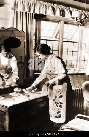 Das Heimleben in den 1940er Jahren in Großbritannien. - Ein Bild aus den 1940er Jahren von einer typischen britischen Hausfrau, die ihr Schlafzimmer putzt. Stockfoto