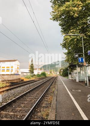 Ein Bahnhof mit einem blauen Schild mit der Aufschrift 1. Die Bahngleise sind leer und der Himmel ist bewölkt Stockfoto