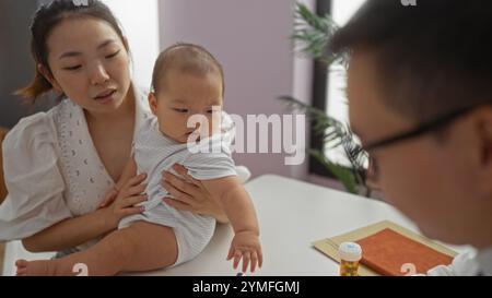 Mutter hält den Jungen in der Kinderarztklinik, während der Arzt mit der Familie im Krankenhauszimmer berät und Liebe und Pflege in einem medizinischen Innenraum zeigt. Stockfoto