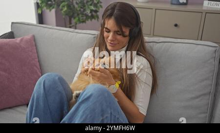 Eine junge Frau genießt die Zeit mit ihrem pommerschen Hund in einem gemütlichen Wohnzimmer Stockfoto