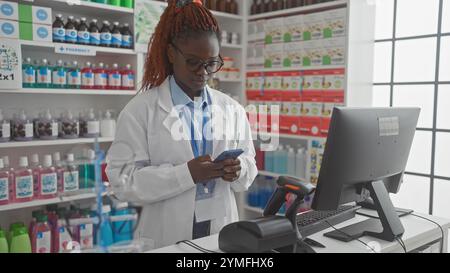 afroamerikanerin Apothekerin mit Smartphone in Drogeriemarkt Stockfoto