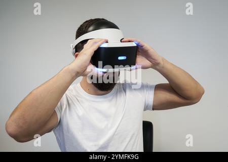 Nahaufnahme eines Mannes mit VR-Headset, der virtuelle Welten mit blauer LED-Beleuchtung erkundet Stockfoto