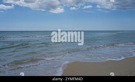 Ein ruhiger Blick auf die klaren Wellen und die Sandküste des Pescolusstrandes unter einem teilweise bewölkten Himmel in salento, apulien, italien. Stockfoto