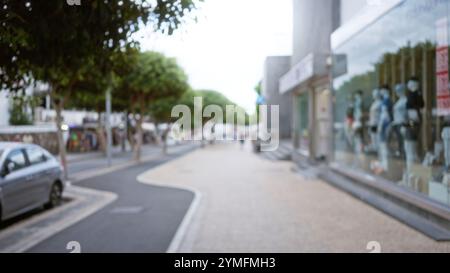 Die Straße im Freien in lanzarote, spanien, zeigt unscharfe Fußgänger, Bäume, Autos und Schaufenster an einem sonnigen Tag Stockfoto