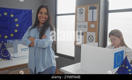 Zwei Frauen nehmen an einer europawahl Teil, eine lächelt und eine andere wählt drinnen neben eu-Flaggen. Stockfoto