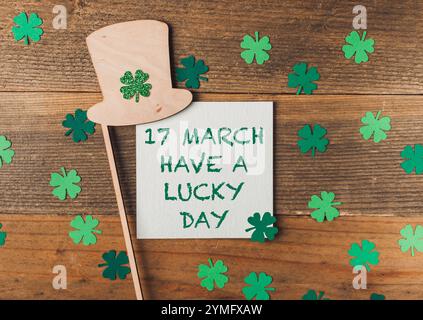 Grüner Schamrock Hut ist auf einer Holzoberfläche mit einem Stück Papier, das besagt, dass der 17. März einen Glückstag haben soll. Stockfoto