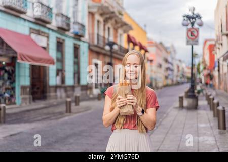 Weibliche Touristen essen Churros auf einer Kolonialstraße in Puebla, Mexiko. Kulturelles Erlebnis, lokale Küche und Streetfood-Konzept Stockfoto