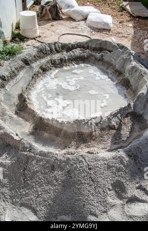 Zementpulverhaufen mit nassem Krater in der Mitte, der manuell mit Schaufel und Hand gemischt werden kann Stockfoto