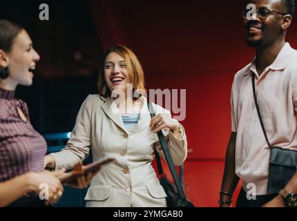 Verschiedene Freunde lachen in lässigen Outfits vor einem leuchtend roten Hintergrund Stockfoto