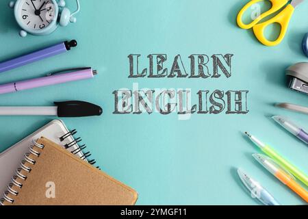 Blauer Hintergrund mit Uhr, Schere, Stiften und Bleistiften. Das Wort Learn english steht in weiß auf dem Hintergrund Stockfoto
