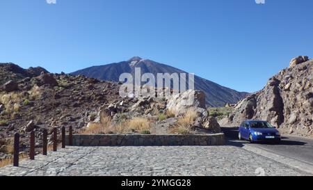 SPANIEN, TENERIFFA - 19. JULI 2014: El Teide. Scenic Mountain Road mit Blue Car in Rocky Landscape Ein blaues Auto fährt entlang einer malerischen Straße, umgeben von Stockfoto