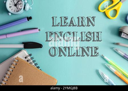 Blauer Hintergrund mit Uhr, Schere, Stiften und Notizbuch. Die Wörter Learn english online stehen in weiß auf dem Hintergrund Stockfoto