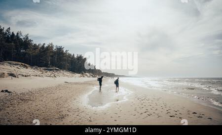 Zwei Personen genießen einen gemütlichen Spaziergang zusammen an einem malerischen Sandstrand, der direkt neben dem weiten und wunderschönen Meer liegt Stockfoto